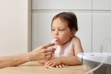 Anne, küçük kızına evde solunum yapıyor.