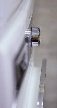 Kadın elinin yakın çekimi çamaşır makinesini çalıştırmak için düğmeye basın. yerli çamaşır makinesi.