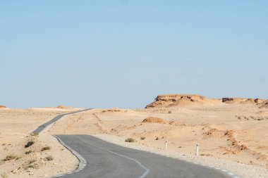 Uçsuz bucaksız Cezayir manzaraları manzaralı bir yol gezisi sırasında çekildi, engebeli araziler, toprak renkleri ve uzak yabanın güzelliği sergilendi.
