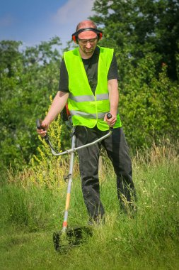 Çim biçme makinesiyle çim biçen işçiler