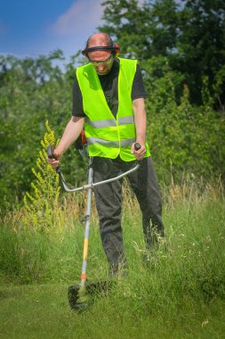 Çim biçme makinesiyle çim biçen işçiler