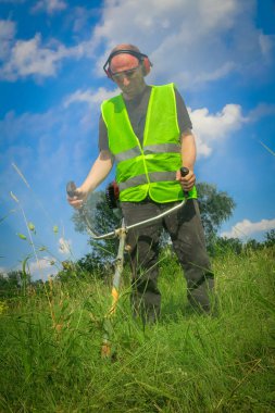 Çim biçme makinesiyle çim biçen işçiler