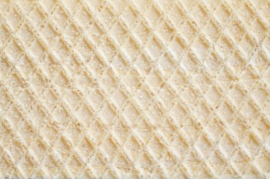 Çıtır bir waffle dokusunun yakın çekimi, altın, ızgara şeklindeki desenini ve çıtır çıtır yüzeyini gözler önüne seriyor. Yemek fotoğrafçılığında veya tasarımda klasik ödüllerin basitliğini ve çekiciliğini vurgulamak için mükemmel..