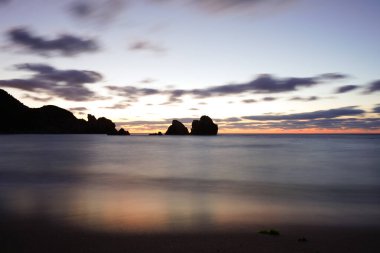 Akşamları kayalıklarla denizde gün batımı