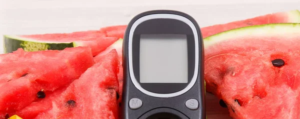 Glucose meter for measuring sugar level and watermelon containing natural minerals, concept of diabetes and healthy nutrition