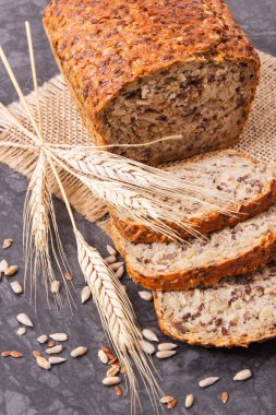 Kahvaltı için taze kepekli ekmek, pişirmek için malzemeler ve çavdar ya da buğday taneleri.