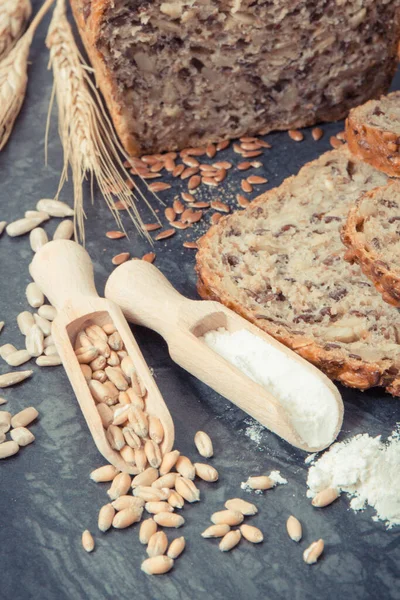 stock image Fresh baked wholegrain bread, ingredients for baking and ears of rye or wheat grain