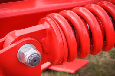 Çelikten yapılmış sert kırmızı yay. Büyük endüstriyel ya da tarımsal makinenin bir parçası. Teknoloji