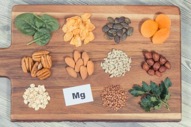 Sağlıklı besleyici yiyecekler ve ahşap kesme tahtasındaki çeşitli malzemeler. Doğal magnezyum, beslenme lifleri ve diğer mineraller