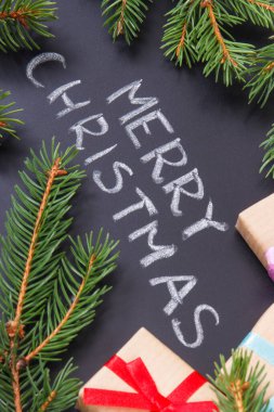 Yazı, Mutlu Noeller, kurdele ve yeşil ladin dallarıyla paketlenmiş hediyeler. Noel zamanı için dekorasyon