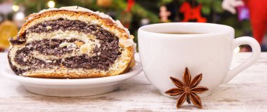 Taze haşhaşlı kek, sıcak çay ya da kahve ve arka planda ışık ve süsleme olan noel ağacı.