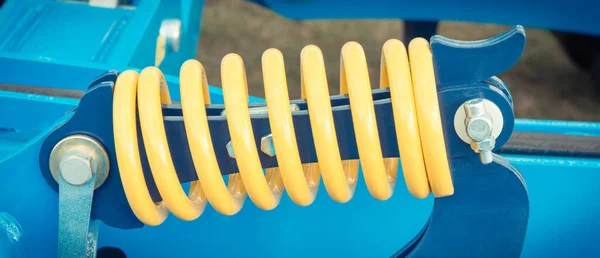 大而硬的黄色弹簧作为蓝色工业或农业机械的一部分和细节 — 图库照片