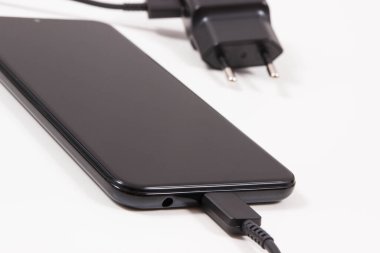 Şarj cihazına bağlı cep telefonu. Akıllı telefon şarj oluyor. Beyaz arkaplan