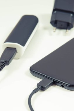 Güç bankasına bağlı akıllı telefon ve şarj aletinin fişi. Telefon şarj oluyor. Beyaz arkaplan