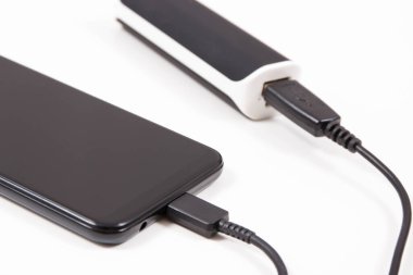 Elektrik prizi bağlı akıllı bir telefon. Telefon şarj oluyor. Beyaz arkaplan