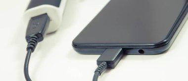 Dış siyah enerji bankası akıllı telefon veya cep telefonunu şarj ediyor. Beyaz arkaplan