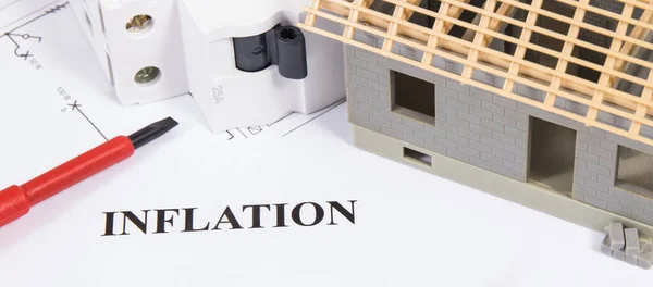Inscriptions inflation with electric fuse, work tools, small toy house under construction and electrical installation plan. Concept of high prices of building home