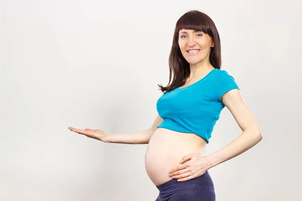 快乐微笑的孕妇空着手拿着短信或不同的产品 期待着新生儿 扩展家庭 — 图库照片