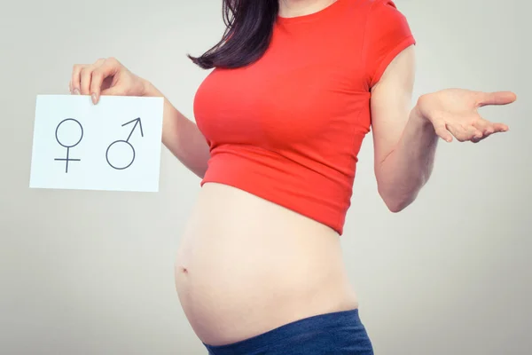 Woman in pregnant holding white card with female and masculine symbol. Expecting birth of girl or boy. Extending family. Motherhood