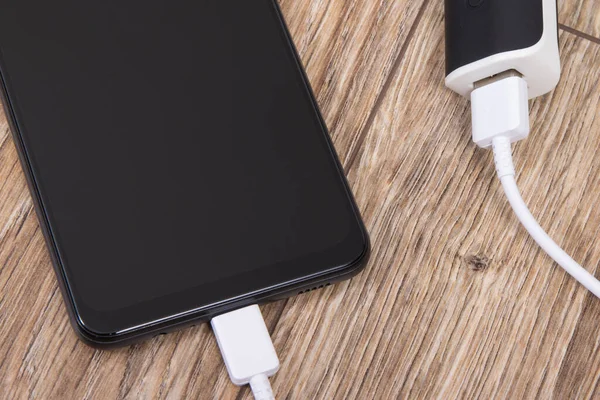 stock image External powerbank using to charge empty battery of black smartphone or mobile phone