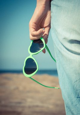 Kalp şeklinde güneş gözlüklü bir kadın eli. Yaz ve tatil zamanı