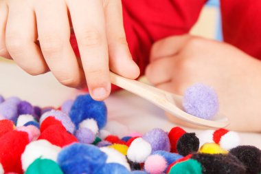 Küçük bebek pompodlarla, tahta kaşıkla ve fincanlarla oynuyor. Çocukların motor becerilerinin, koordinasyonun, yaratıcılığın ve mantıksal düşüncenin geliştirilmesi