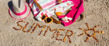 Yazın, kehribar taşı ve aksesuarlardan oluşan güneş şeklinde bir yazı. Rahatlamak için ya da kumsalda güneşlenmek için. Seyahat, turizm ve tatil zamanı kavramı