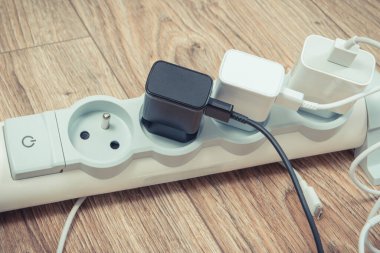 Mobile phone chargers connected to electrical power strip. Various devices charging concept