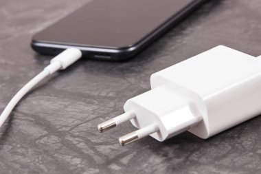 Şarj aletine bağlı siyah akıllı telefon. Telefon şarj ediliyor.