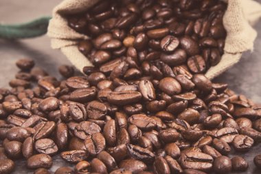 Koyu kavrulmuş kahve tanecikleri, beton yapının üzerinde jüt poşetinde. Vintage fotoğraf