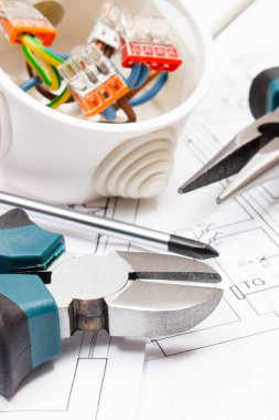 Çalışmak için kullanılan metal aletler, renkli kablolarla bağlı elektrik kutusu ve elektrik tesisatı olan konut planının diyagramları. Ev konsepti inşa ediliyor