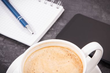 Cep telefonu, not almak için sütlü kahve ve not defteri. Çalışma ya da dinlenme zamanı