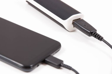 Elektrik prizi bağlı akıllı bir telefon. Telefon şarj oluyor. Beyaz arkaplan