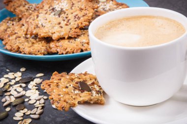 Sütlü kahve ve mavi tabakta taze ev yapımı yulaf ezmeli kurabiye. Lezzetli çıtır tatlı.