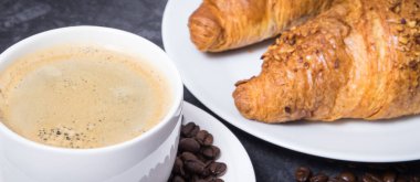 Taze pişmiş kruvasan, çikolatalı ve beyaz cam bardakta kahveden oluşan kahvaltı.