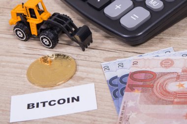 Bitcoin, euro faturaları, minyatür kazıcı ve hesap makinesi. Kripto para biriminin sembolü. Uluslararası ağ ödemesi. Finans kavramı