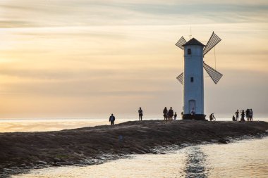 Swinoujscie, Batı Pomeranya - Polonya - 14 Haziran 2021: Yel değirmeni Stawa Mlyny 'de gün batımında. Karakteristik yön bulma işareti ve deniz feneri