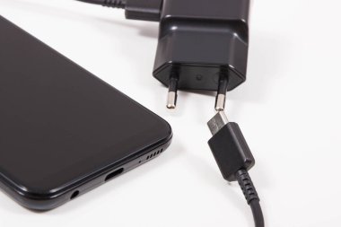 Cep telefonu ve şarjlı şarj aleti. Akıllı telefon şarj oluyor. Beyaz arkaplan