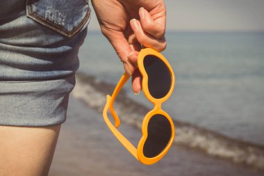 Kalp şeklinde güneş gözlüklü bir kadın eli. Yaz ve tatil zamanı. Vintage fotoğraf