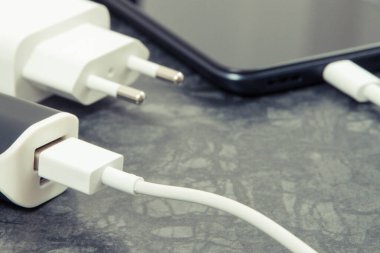 Dış güç bankasının bağlı beyaz fişi olan siyah akıllı telefon. Cep telefonu şarj ediliyor