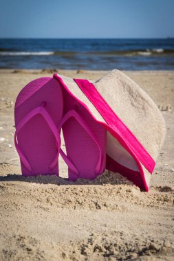 Kumsalda dinlenmek için aksesuarlar. Hasır şapka ve pembe parmak arası terlik. Yaz zamanı.