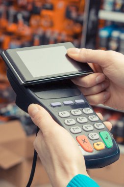 Ödeme terminali ve akıllı telefonu kullanan bir kadın eli. Temassız ödeme. Dükkanda alışveriş için para ödemeden. Finans kavramı