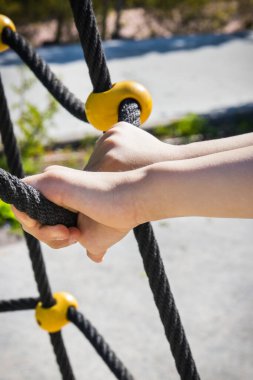 Anaokulunun elleri ve yaz parkında oyun parkına tırmanmak için siyah ip. Çocuk gelişimi kavramı