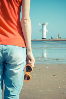 Batı dalgakıranında kalp şeklinde güneş gözlüklü bir kadın. Arka planda Swinoujscie 'deki Windmill Stawa Mlyny. Yaz ve tatil zamanı