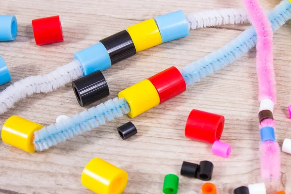 Thread, creative sticks and colorful beads used to making bracelets, learn counting and arranging various shapes. Development of kids motor skills, creativity, coordination and logical thinking