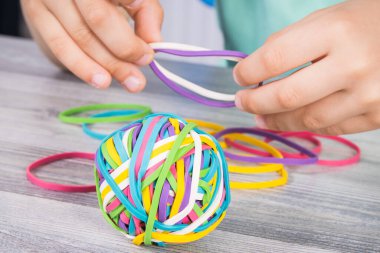 Anaokulunun elleri renkli lastik bantlarla ya da silgiyle oynuyor. Çocukların motor becerilerinin, koordinasyonun, yaratıcılığın ve mantıksal düşüncenin geliştirilmesi