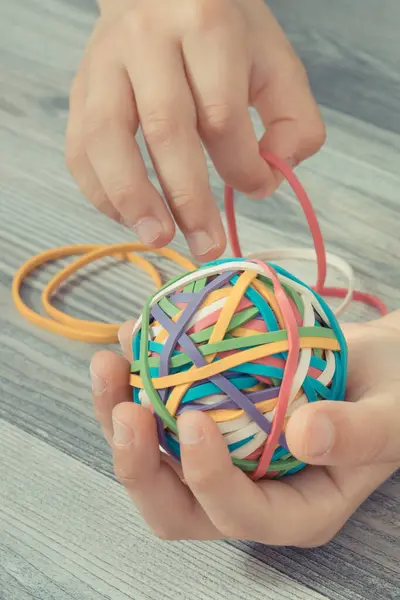 Preschooler hands with ball of colorful rubber bands or erasers. Development of kids motor skills, coordination, creativity and logical thinking