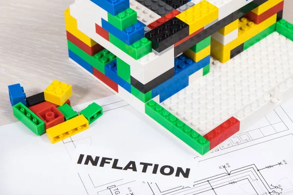 Housing plan with electric installation, house under construction made of colorful toy blocks, inscription inflation. Subject of building or renting home