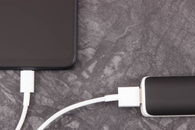 Dış siyah enerji bankası akıllı telefon veya cep telefonunu şarj ediyor. Metin veya yazı için yer
