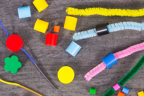 Thread, creative sticks and colorful beads used to making bracelets, learn counting and arranging various shapes. Development of kids motor skills, creativity and logical thinking